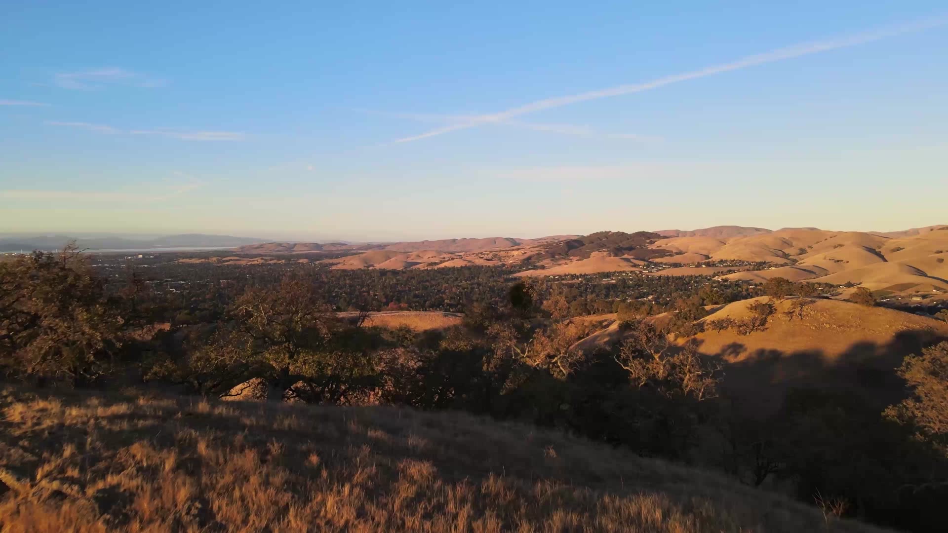Aerial view of golden South Bay foothills and a valley neighborhood at sunset, illustrative